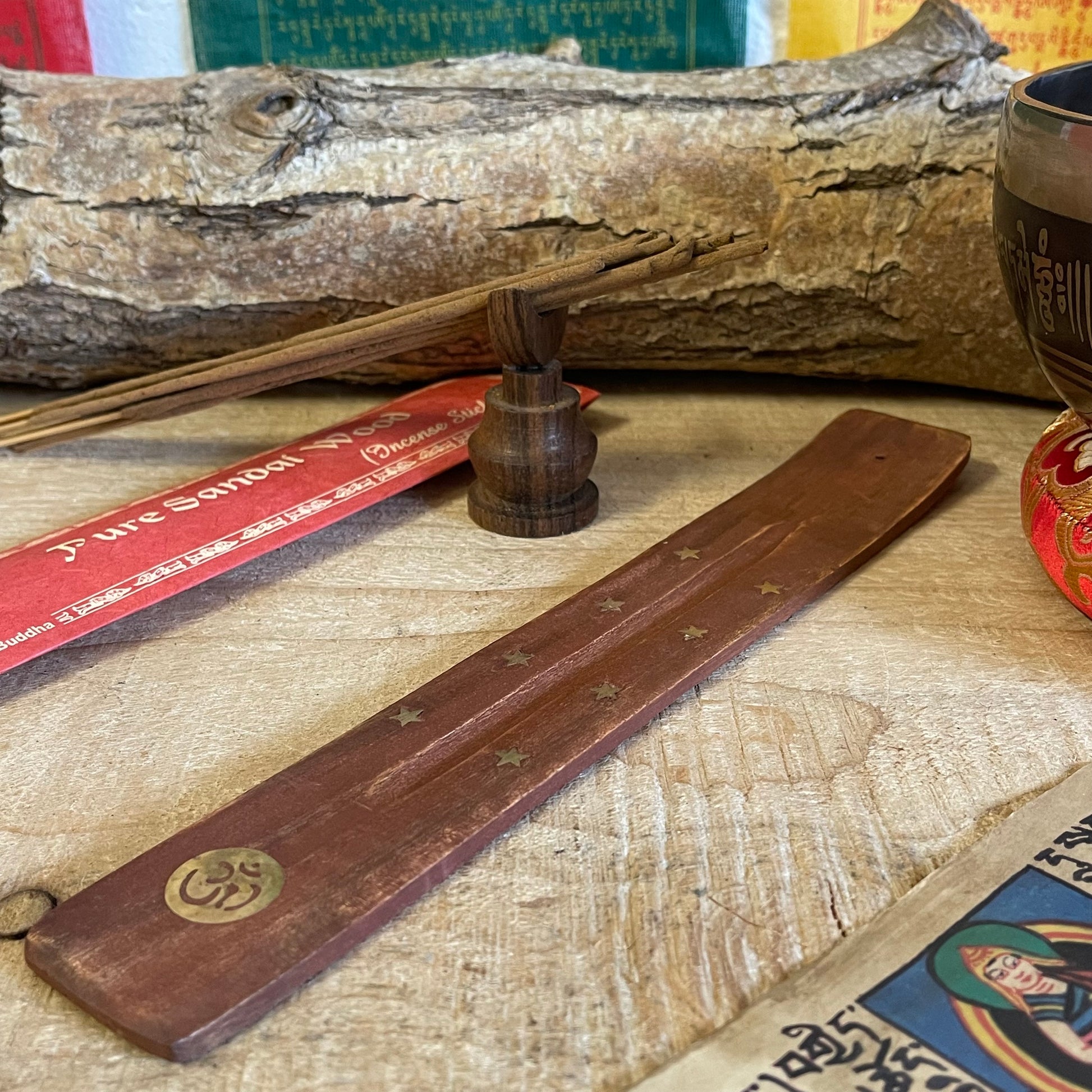Introducing our most popular incense holder, crafted from beautiful mango wood in a unique shoe horn design. This ash catcher is perfect for stick incense, featuring elegant inlays of stars and the sacred Om sign.
With its thoughtful design, the incense rests securely over the wooden body, allowing ash to collect neatly as it falls, keeping your space clean and serene.