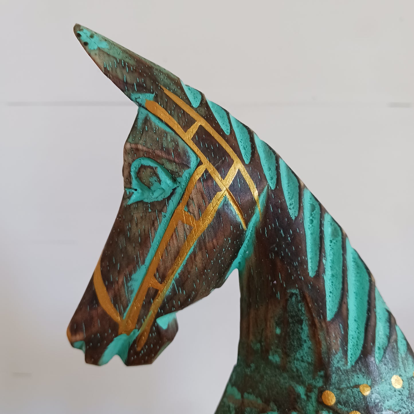Add a touch of exotic equine elegance to your home with this beautiful hand carved decorative horse figure. Handcrafted from high-quality albasia wood in Indonesia, this striking piece features intricate carvings highlighted in gold and turquoise accents, creating a stunning contrast.