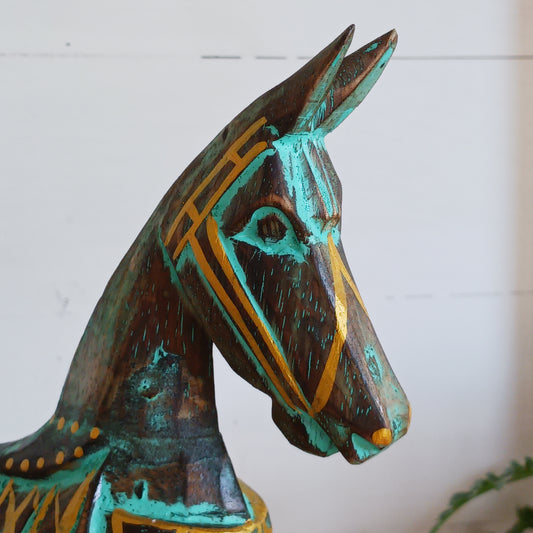Add a touch of exotic equine elegance to your home with this beautiful hand carved decorative horse figure. Handcrafted from high-quality albasia wood in Indonesia, this striking piece features intricate carvings highlighted in gold and turquoise accents, creating a stunning contrast.