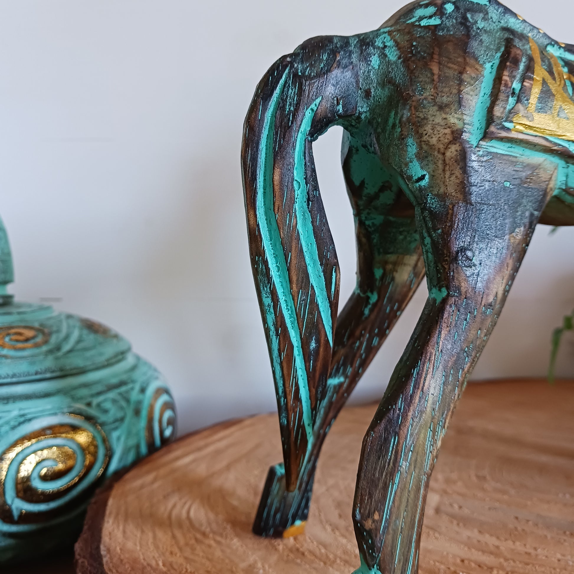 Add a touch of exotic equine elegance to your home with this beautiful hand carved decorative horse figure. Handcrafted from high-quality albasia wood in Indonesia, this striking piece features intricate carvings highlighted in gold and turquoise accents, creating a stunning contrast.