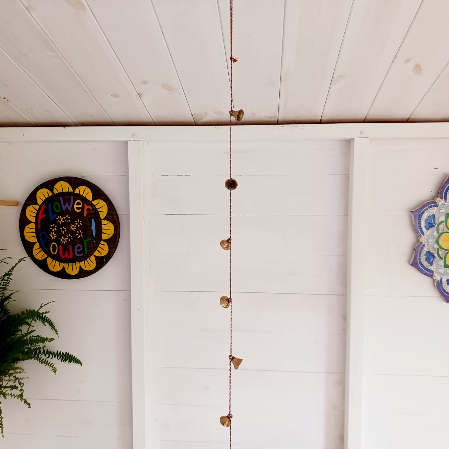 This delightful string of eleven Indian brass bells, hung on a length of rainbow coloured cord. This lovely little string of bells makes a wonderful gentle jingle sound when hung in the breeze.