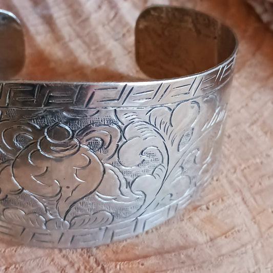 Handcrafted from Tibetan white metal, this elegant bracelet is delicately hand-etched with various Buddhist symbols, including the Endless Knot.