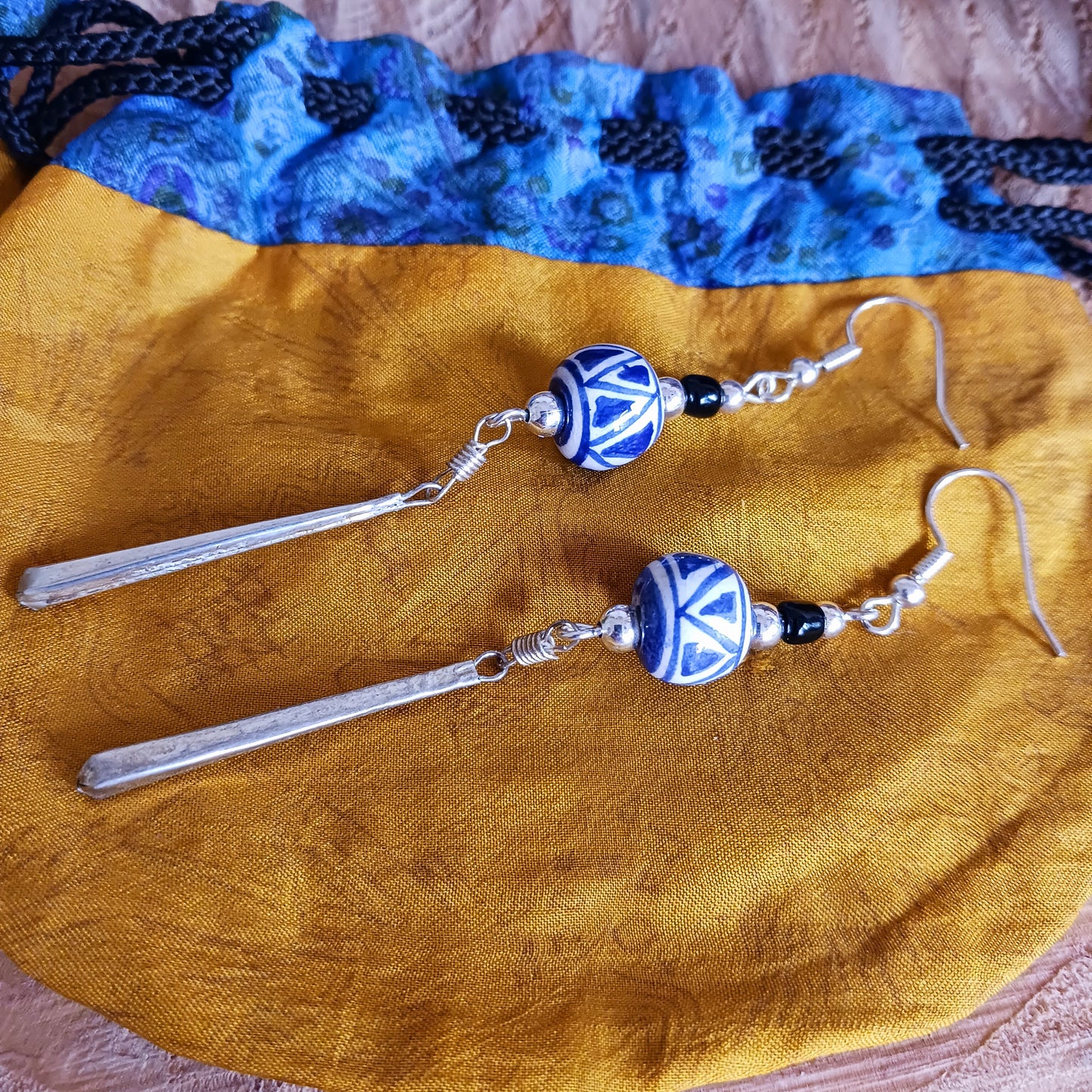 These pretty and stylish blue and white earrings have been handmade from clay beads from Cusco, Peru. Each earring features a unique hand-painted pattern that will remind of summer.