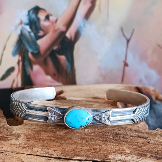 This bracelet is a stunning example of classic Navajo jewellery. This piece is handmade out of sterling silver and genuine Turquoise oval stone.  The Arrows are for protection.