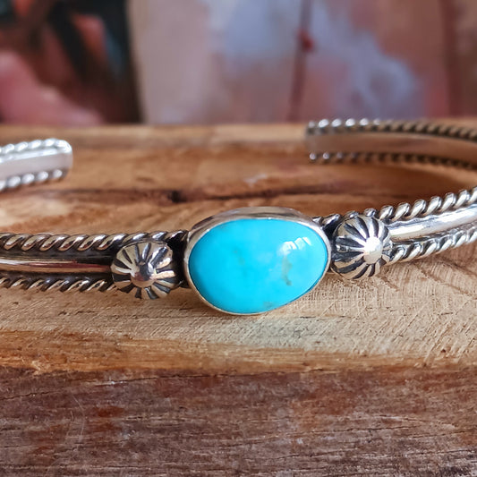 This beautiful and elegant Kingman Turquoise bracelet has been handmade by Navajo artisan Ben Jimenez.  The finely crafted silver band is complemented by a stunning Turquoise stone at the centre. This is the artistry of Ben Jimenez who has developed such a distinctive style.