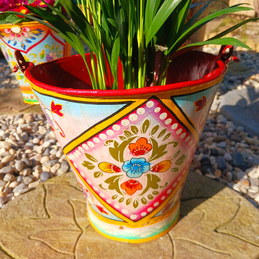 Hand painted in a pink floral design, a vintage style iron plant pot to display as a decorative indoor/outdoor planter. 
 Lovingly hand painted by skilled artisans on a fair trade basis in the Indian desert city of Jodhpur. Fill the striking container with a flowering or contrasting potted plant. Grow seasonal bulbs to bring life and inspiration.