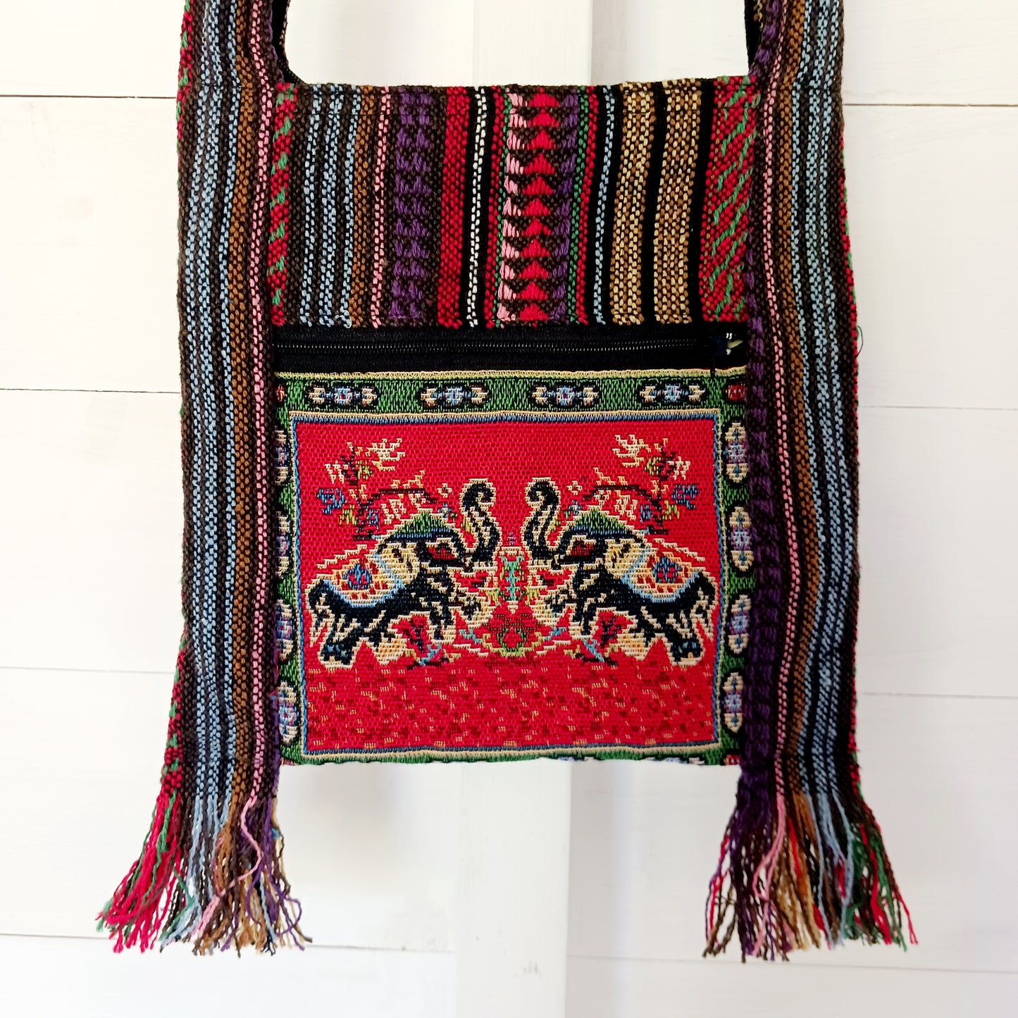 This handy little shoulder bag has a wide strap that is long enough to use as a shoulder or crossbody bag and also makes it comfortable to wear for long periods. The main fabric is traditional with a beautiful embroidered decorated elephants on the front. The bag is finished with tassels.