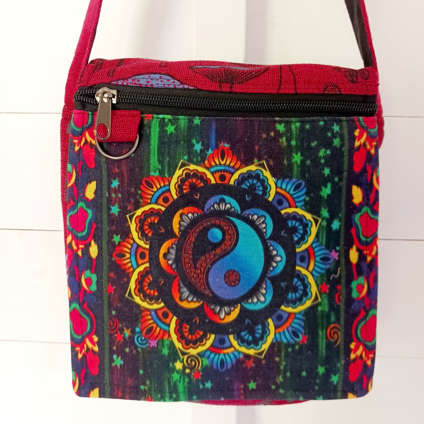 This lovely Yin Yang shoulder bag is both practical and unusual. There are three zipped compartments ensuring you keep your valuables safe. The Yin Yang design on the front is set in a colourful mandala on the flap, and this is secured with a velcro strips. The staps are adjustable to suit your style.