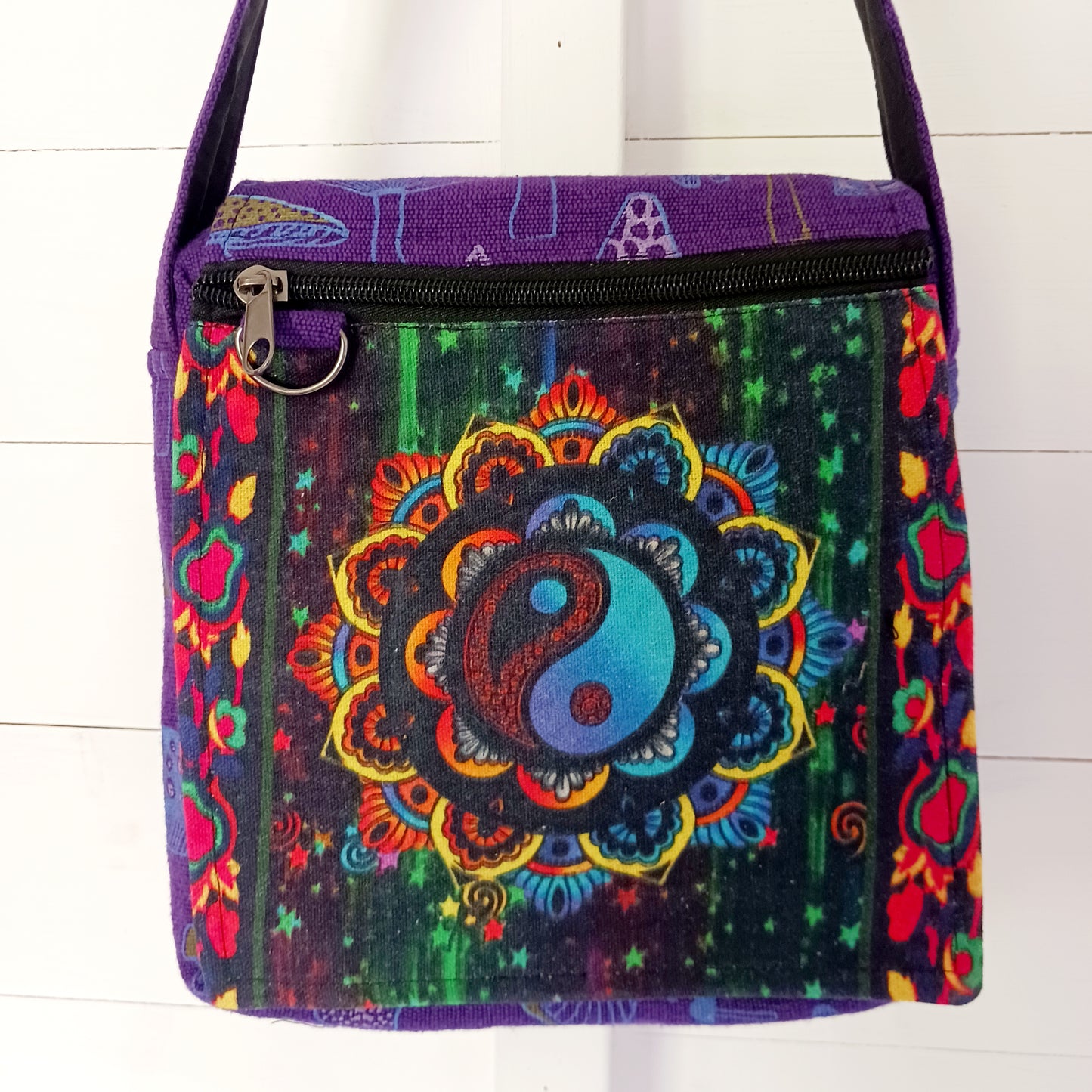 This lovely Yin Yang shoulder bag is both practical and unusual. There are three zipped compartments ensuring you keep your valuables safe. The Yin Yang design on the front is set in a colourful mandala on the flap, and this is secured with a velcro strips. The staps are adjustable to suit your style.