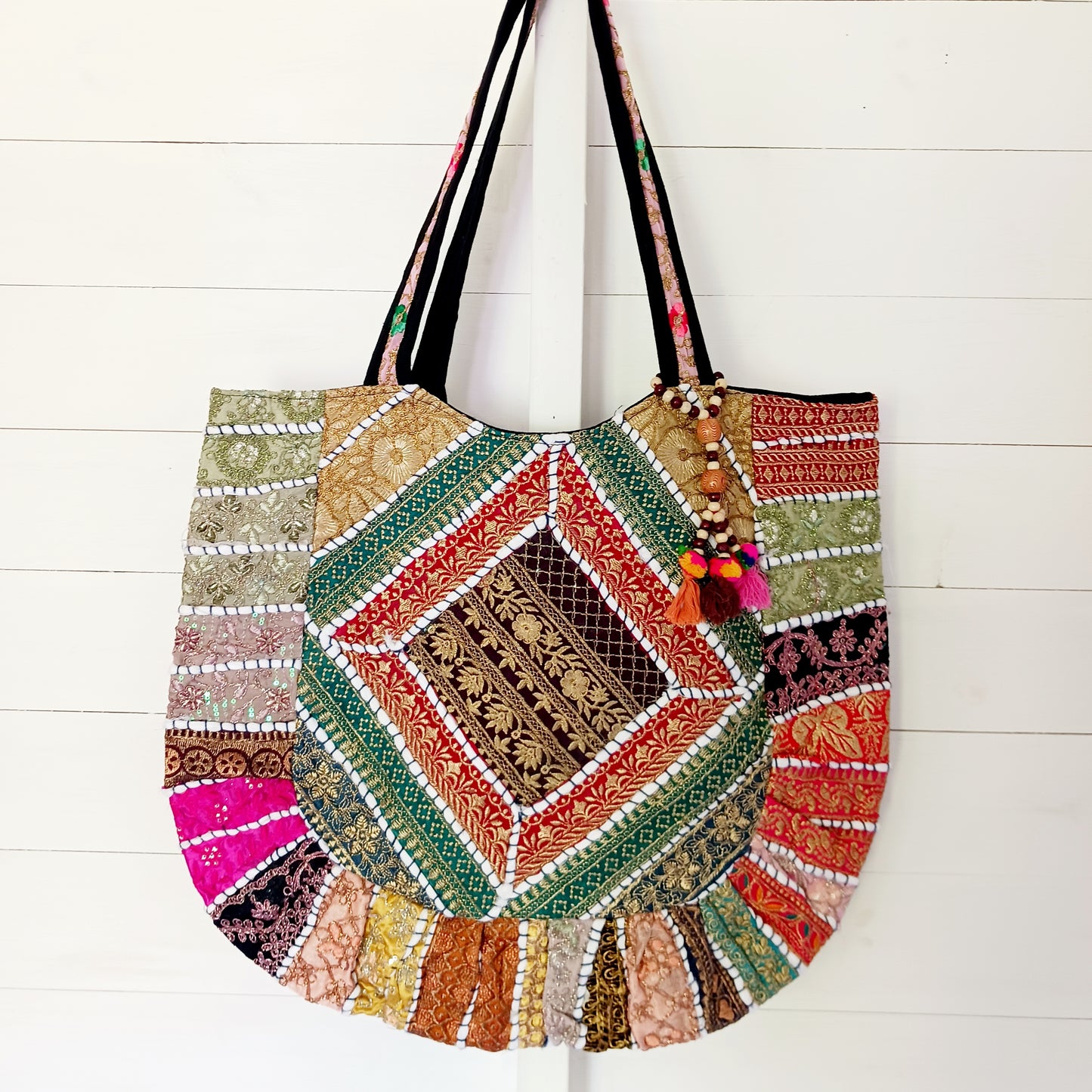 This beautiful large Indian tote bag comes with a wide shoulder strap and plenty of space inside for your personal items. In a patchwork style design, this bag is intricately embroidered with a traditional bohemian pattern. The bag comes decorated with beads and pom poms and is fully lined throughout.