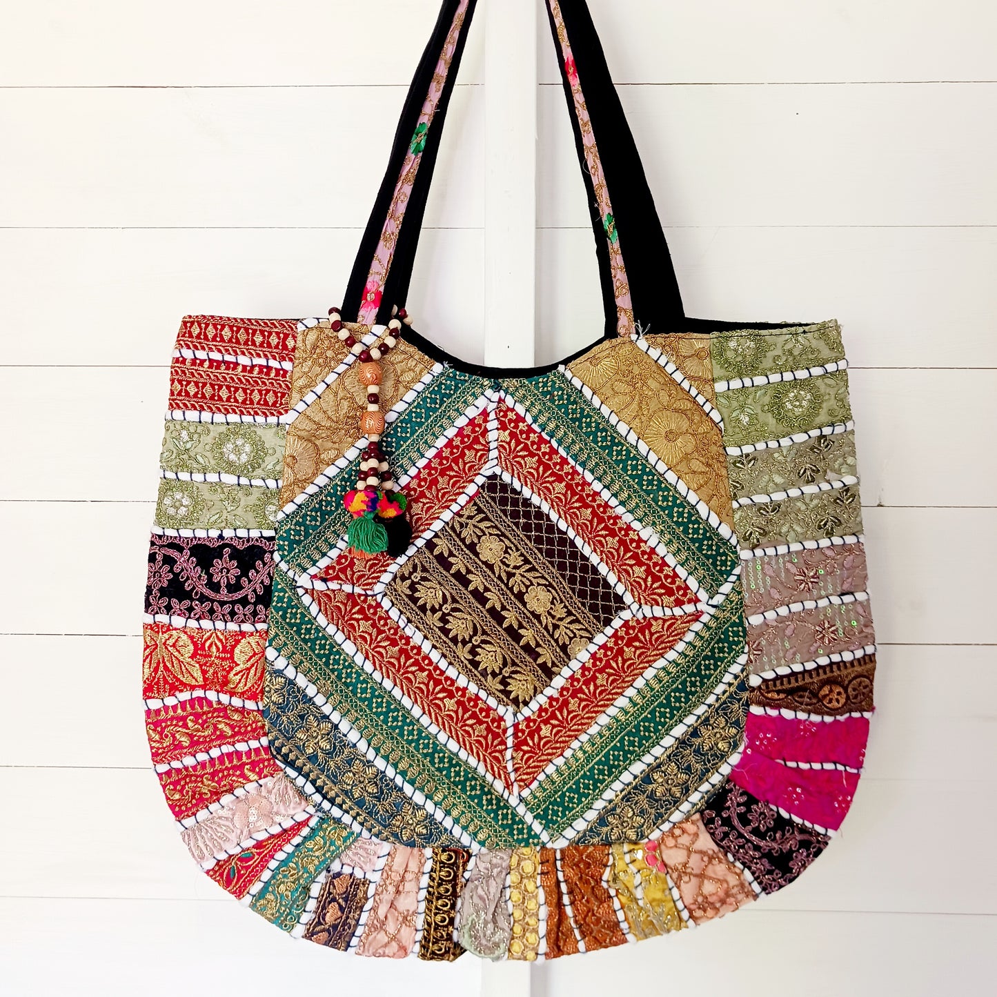This beautiful large Indian tote bag comes with a wide shoulder strap and plenty of space inside for your personal items. In a patchwork style design, this bag is intricately embroidered with a traditional bohemian pattern. The bag comes decorated with beads and pom poms and is fully lined throughout.