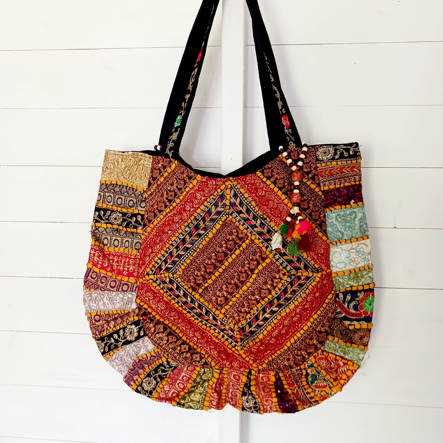 This beautiful large Indian tote bag comes with a wide shoulder strap and plenty of space inside for your personal items. In a patchwork style design, this bag is intricately embroidered with a traditional bohemian pattern.The bag comes decorated with beads and pom poms and is fully lined throughout.