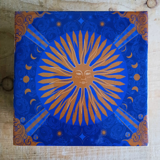 Illuminate your space with the Hop Hare Big Enamelled Square Box, a handcrafted treasure that blends beauty, spirituality, and functionality. Made from sustainable mango wood and adorned with deep blue enamel, this large storage box features a radiant golden sun design symbolizing success, confidence, joy, and vitality.