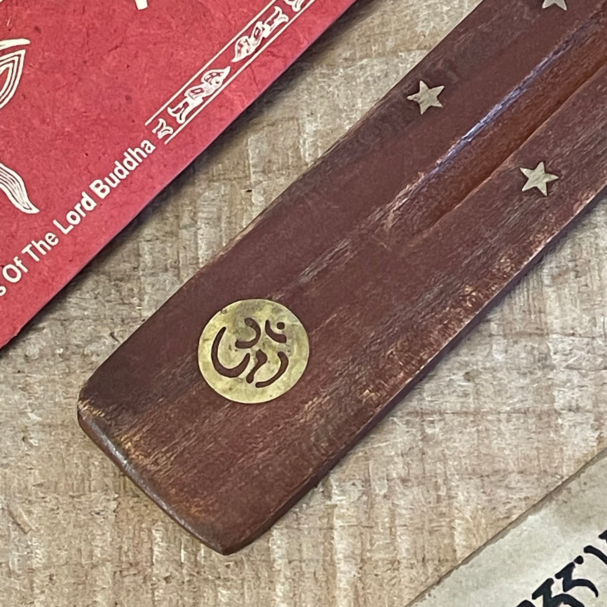 Introducing our most popular incense holder, crafted from beautiful mango wood in a unique shoe horn design. This ash catcher is perfect for stick incense, featuring elegant inlays of stars and the sacred Om sign.
With its thoughtful design, the incense rests securely over the wooden body, allowing ash to collect neatly as it falls, keeping your space clean and serene.