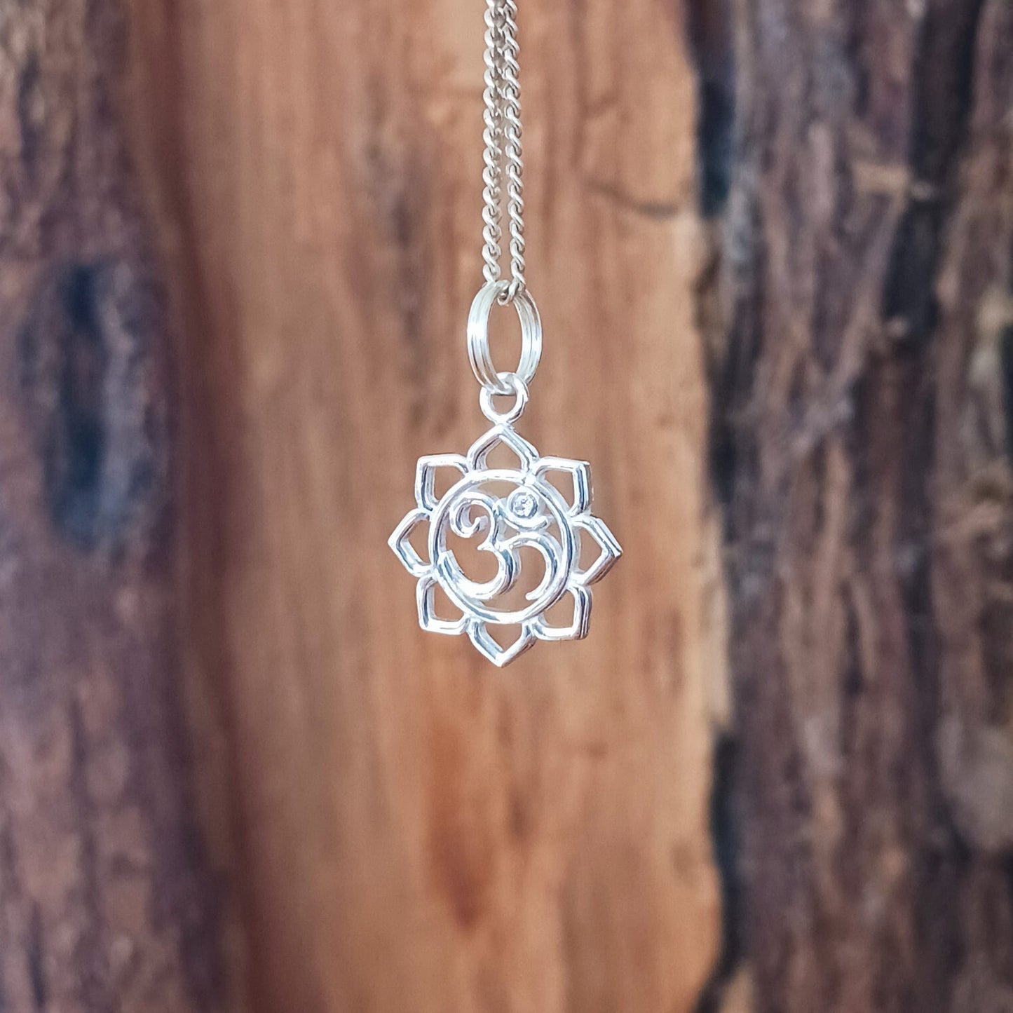 This lovely Om Symbol in Lotus silver pendant has a tiny embedded zirconia stone and comes with a fine solid 925 silver chain. Om or (Aum) is a sacred sound considered by many ancient philosophical texts to be the sound of the universe, encompassing all other sounds within it. In Sanskrit, om is called Pranava, which means to hum, and is considered an unlimited or eternal sound.