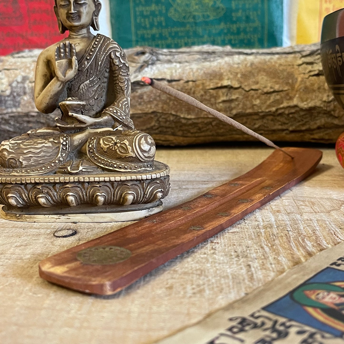 This popular shoehorn-style incense holder, crafted from mango wood, serves as both a beautiful and functional ash catcher. The design is adorned with brass inlays featuring stars and the Flower of Life, a symbol representing the interconnectedness of life. Its long, slightly curved shape securely holds stick incense, with the wooden base effectively catching falling ash to keep surfaces clean.