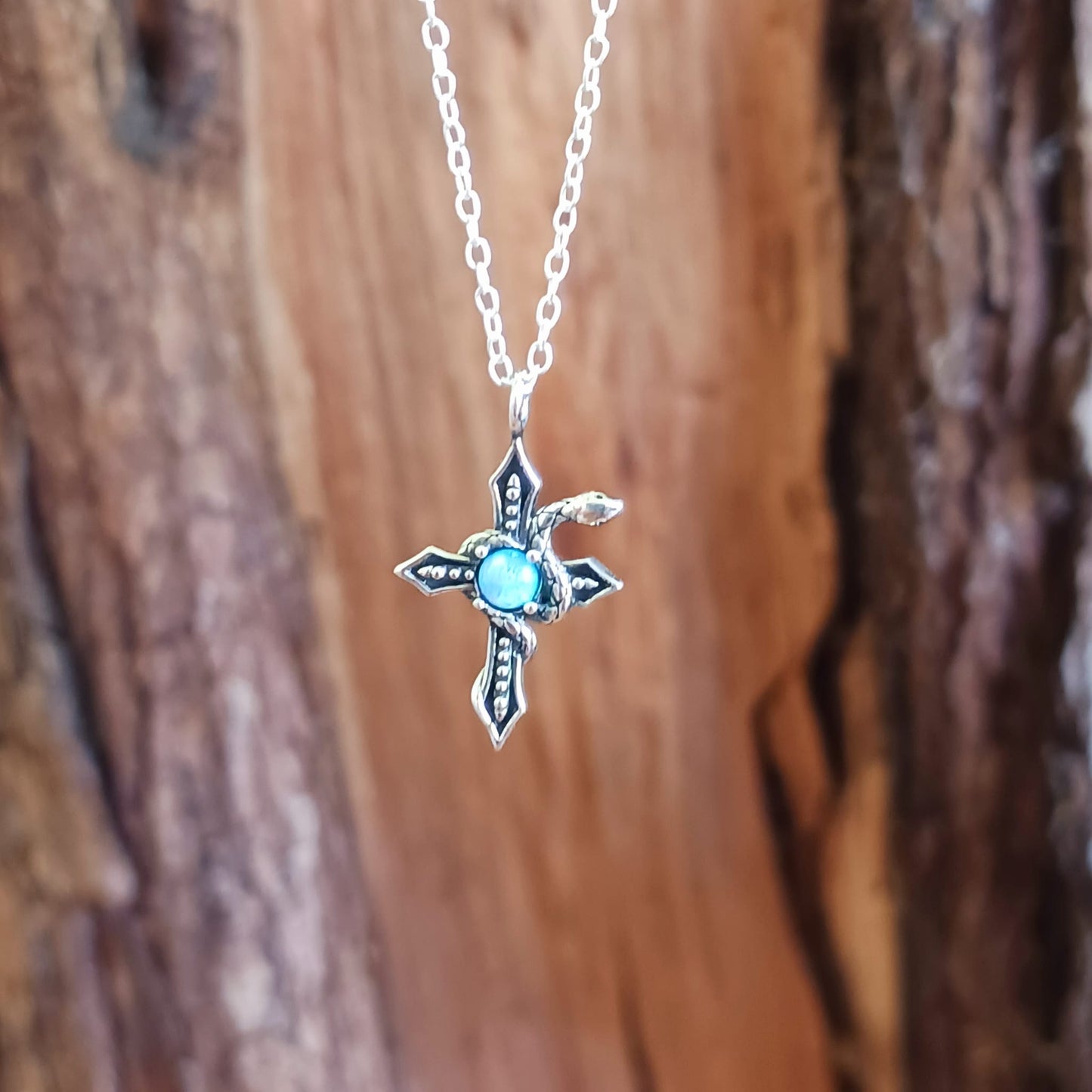 This detailed sterling silver cross has a silver serpent wrapped around it and comes with a beautiful Azure stone in the centre. The cross is held on a 925 silver chain. The snake is thought to represent transformation and rebirth, symbolizing the shedding of old skin and embracing new beginnings. The cross, a powerful symbol of faith and spirituality, adds an element of devotion and divine connection to the design.