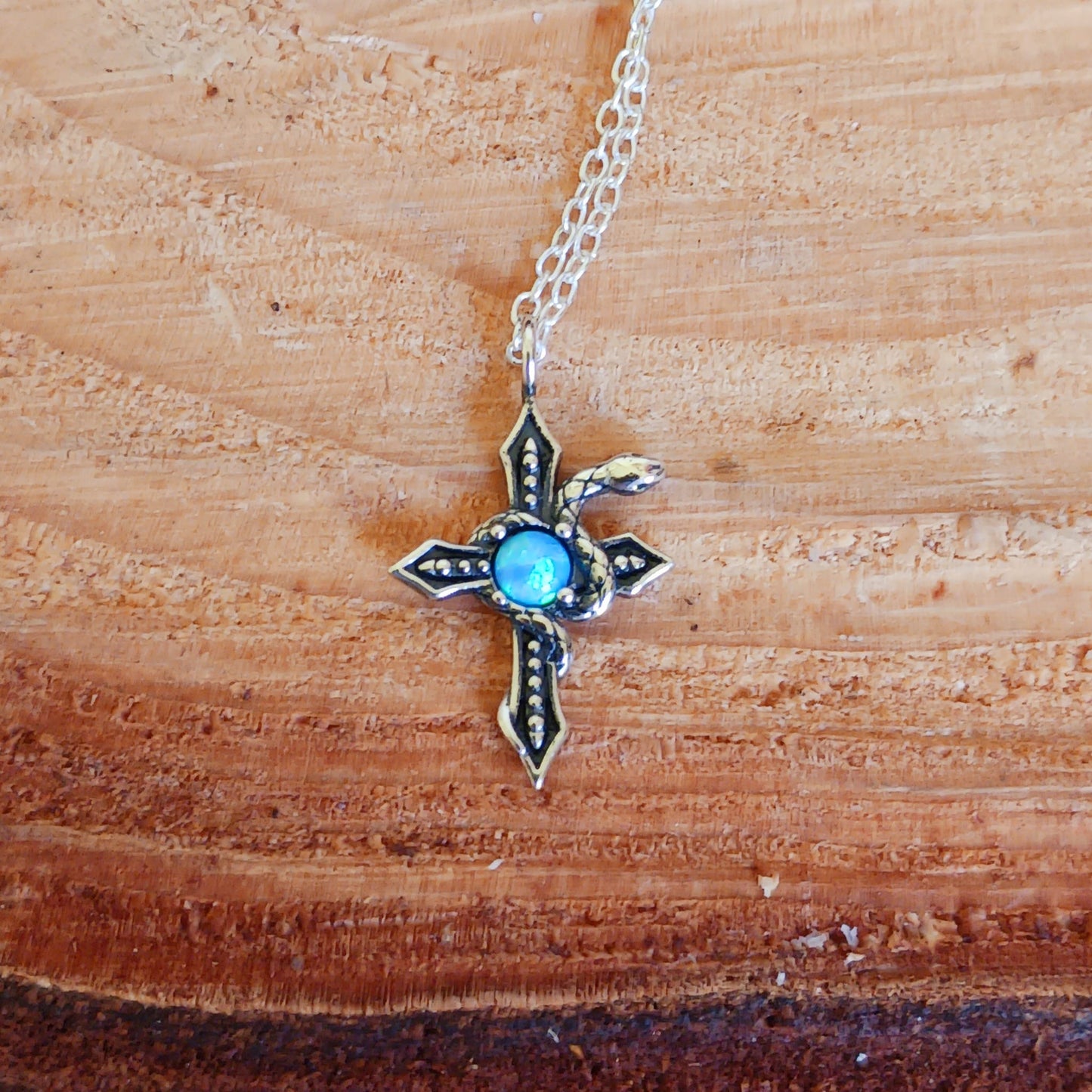 This detailed sterling silver cross has a silver serpent wrapped around it and comes with a beautiful Azure stone in the centre. The cross is held on a 925 silver chain. The snake is thought to represent transformation and rebirth, symbolizing the shedding of old skin and embracing new beginnings. The cross, a powerful symbol of faith and spirituality, adds an element of devotion and divine connection to the design.