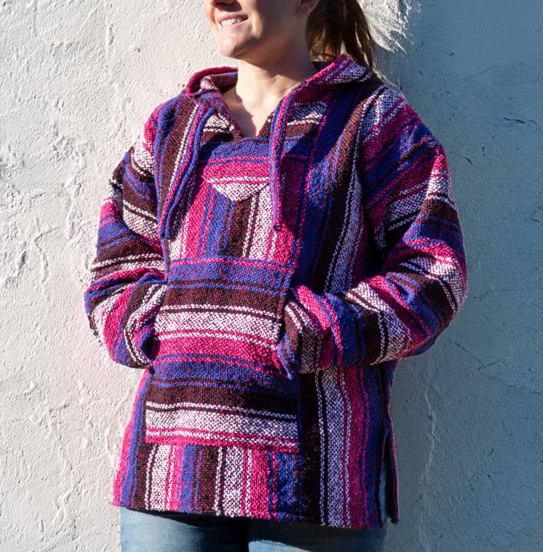 Wrap yourself in warmth and colour with this Mexican Pink Baja Top, a vibrant expression of bohemian spirit and ethical craftsmanship. The bold blues and pinks weave together in a striking pattern that reimagines the classic Baja design for the modern free soul.
Each hoodie is ethically sourced from Mexico, where skilled artisans create them with care, ensuring fair wages and safe working conditions. The soft, brushed interior offers comfort against the skin, while the relaxed, unisex fit makes it perfect