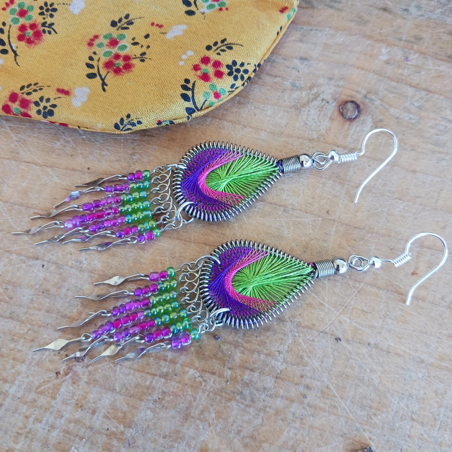 These beautiful and eye-catching earrings are handmade in Peru and feature an array of gorgeous colours. A woven teardrop, similar in style to a peacock feather, is finished with co-ordinating beads and silver embellishments. Ideal for a night out or for dressing up your boho look!