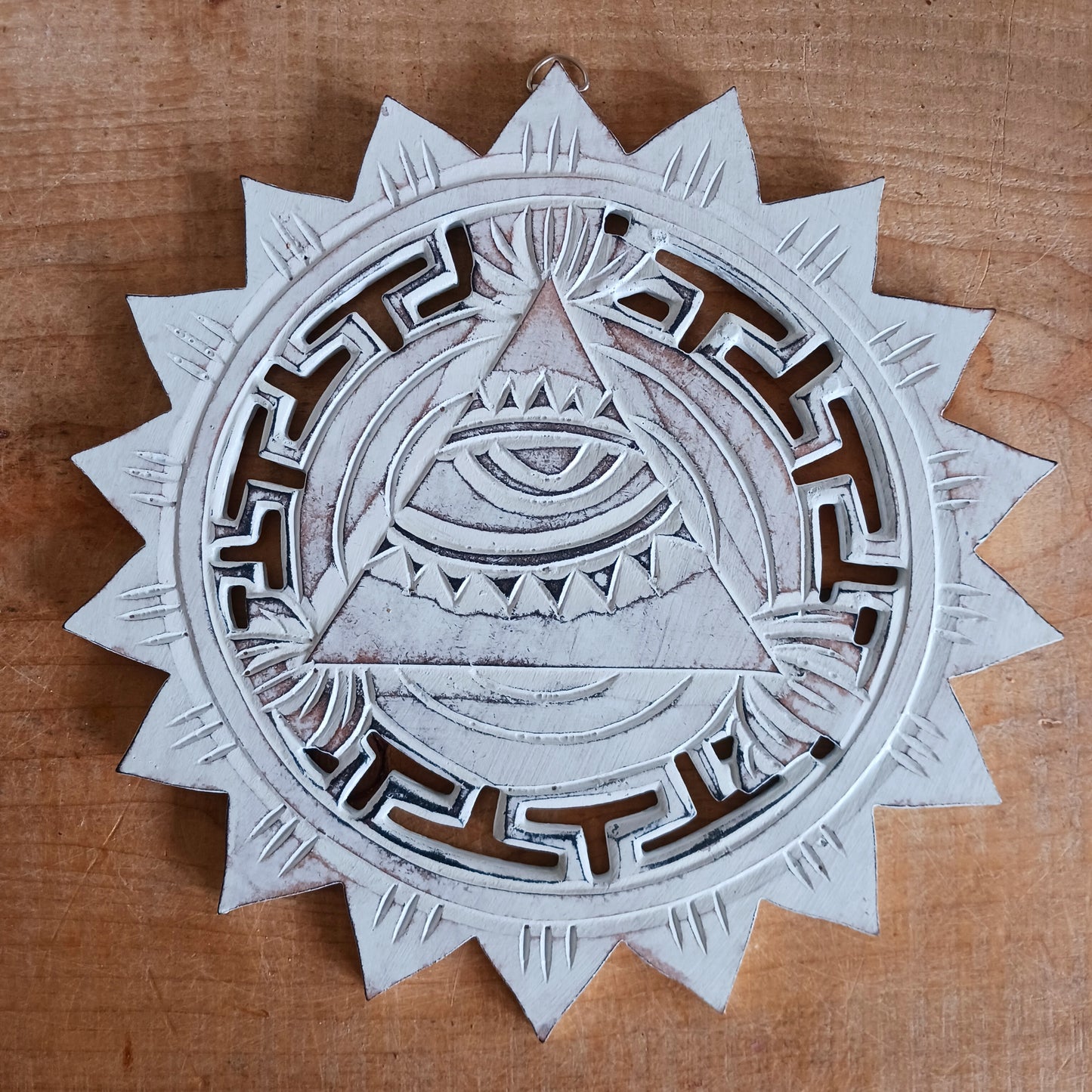 This wooden plaque has been intricately carved by hand to represent the Eye of Providence. The Eye of Providence or All-Seeing Eye is a symbol depicting an eye, often enclosed in a triangle and surrounded by a ray of light or a halo, intended to represent Providence, as the eye watches over the workers of mankind. In Christianity it serves as a reminder that humanitiy's thoughts and deeds are always obserbed by God.