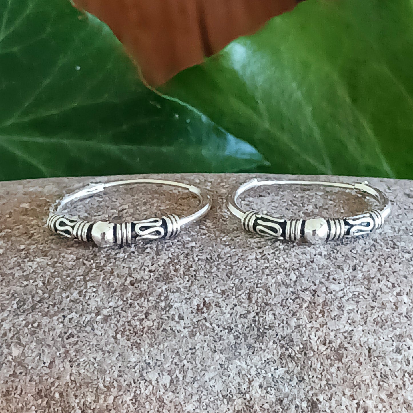 These sterling silver hoop earrings showcase a stunning Bali-inspired design, perfect for adding a touch of elegance to your boho-chic style. The intricate craftsmanship features a delicate silver ball accent at the center of each hoop, embodying a timeless and versatile aesthetic.