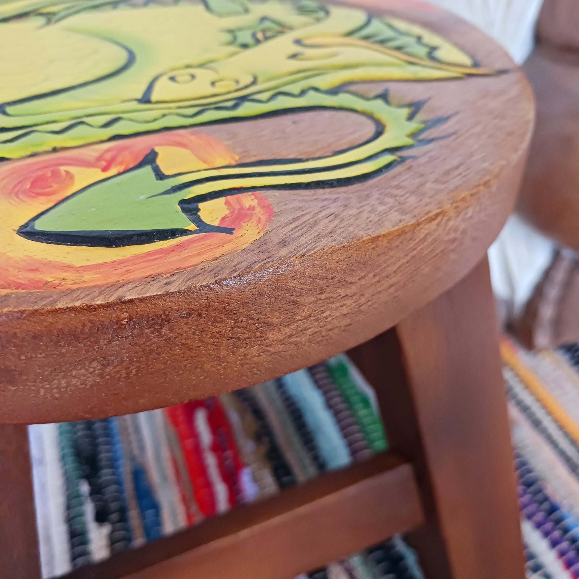 This lovely little handmade, carved and painted stool is Fairtrade from Thailand. The top of this stool has been carefully hand carved and then painted to show a peacefully curled, sleeping dragon surrounded by flames. These cheeky little items are very versatile making great stools for little bums or as tiny tables to add accent to your home. They can also be very useful as a step for those hard to reach high up shelves or even just to put your feet up on, and due to their small form are easy to store.