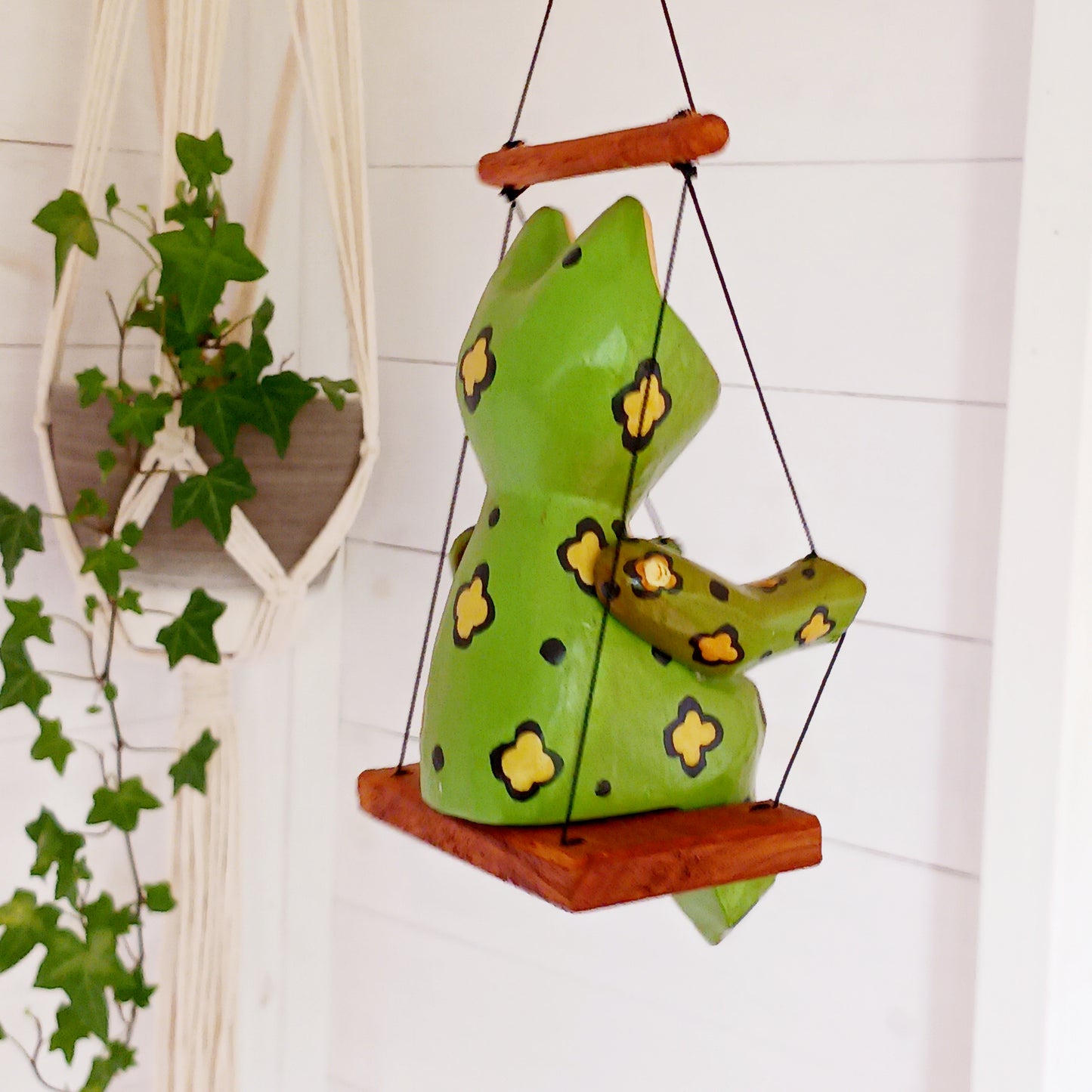 Add charm and whimsy to any space with this adorable hand-carved wooden frog! Perched on a swing and suspended by a long spring, this frog bounces gently in the air, bringing playful motion and joy to any room. Each piece is carefully hand-painted and carved from fast-growing, sustainably harvested albesia wood, making it a more eco-friendly choice for softwood décor. Whether for a nursery, porch, or creative space, this eye-catching novelty is sure to delight kids and adults alike!