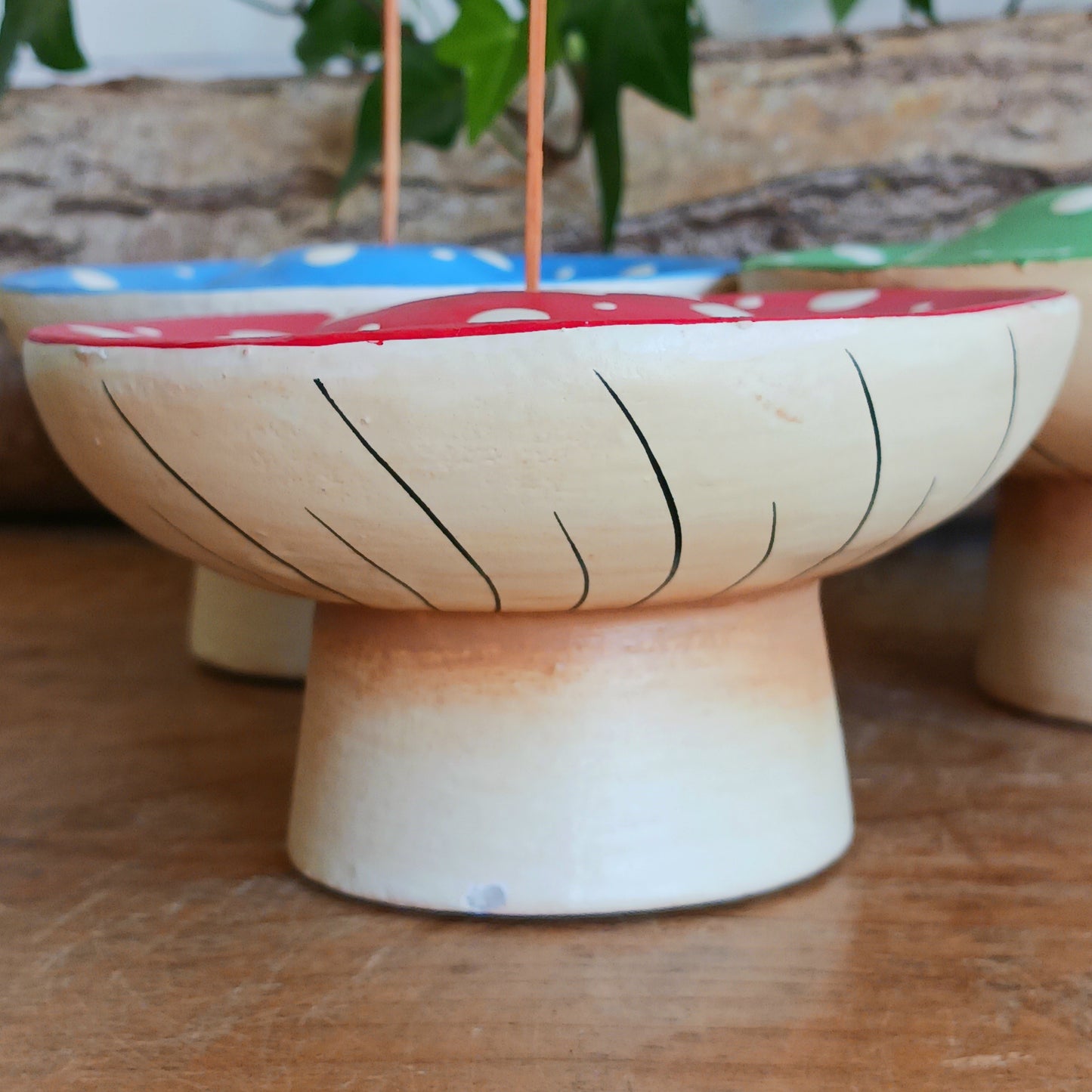 Bring woodland charm to your space with these hand-painted wooden mushroom incense holders. Each piece features a white stalk and a vibrant, spotty cap in your choice of blue, green or red. Designed with a central incense stick holder, these mushrooms are perfect for adding a whimsical, on-trend touch to your décor.