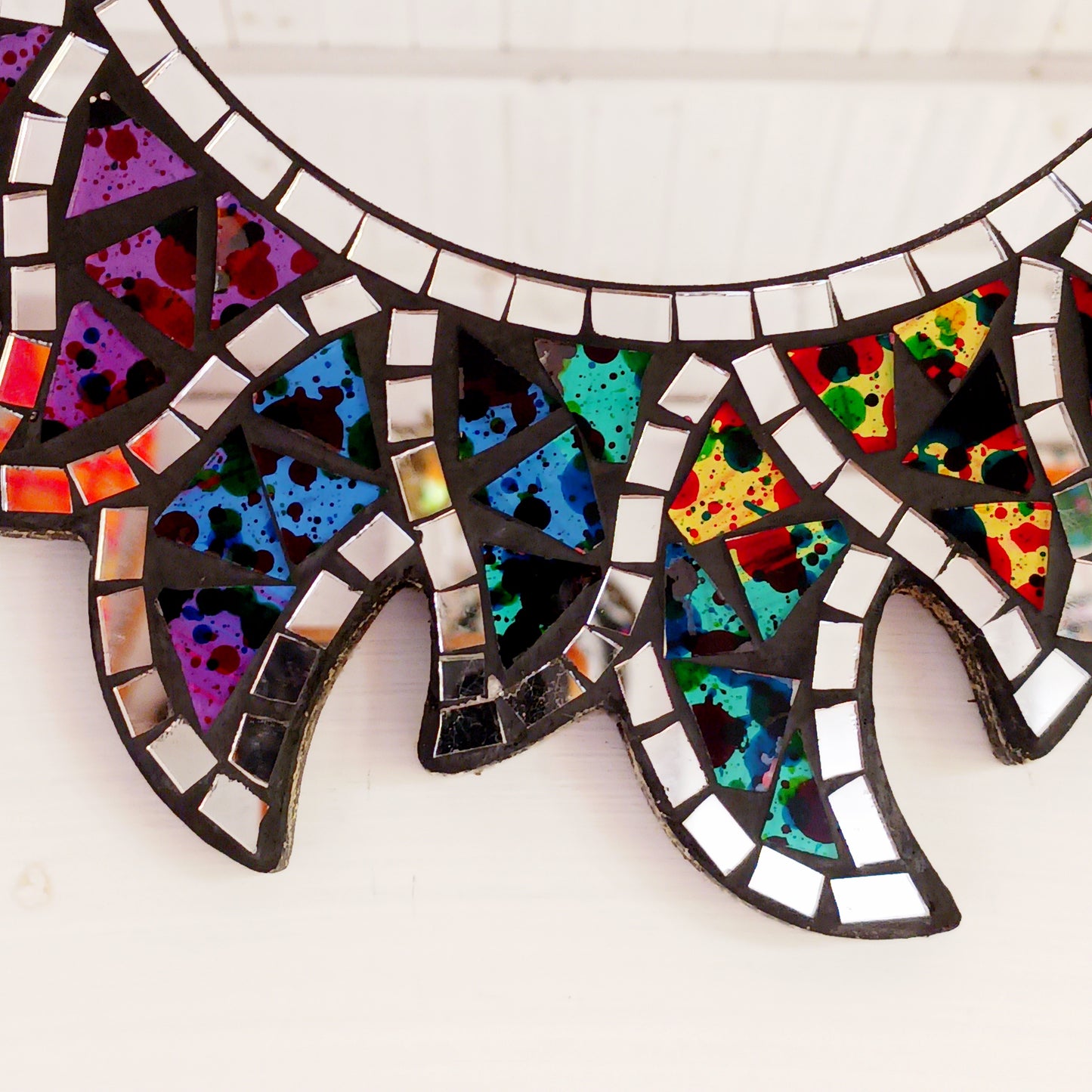 This beautiful sun shaped mirror is decoration with multicoloured glass mosaic tiles and finished on albesia wood frame. There is a hook on the back for hanging.