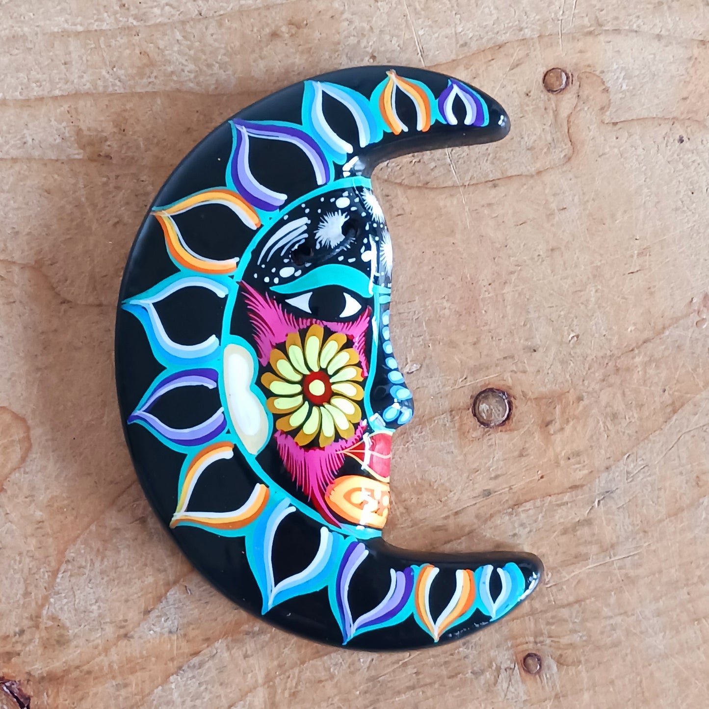 This vibrant wall plaque will have you over the moon! Expertly hand-painted in the bold, colorful style traditional to Xalitla in Guerrero, Mexico, this eye-catching piece celebrates the beauty of authentic Mexican folk art. A striking glaze enhances its vivid design, making it a stunning focal point in any room. The plaque includes two small holes for adding a hanging loop, allowing for easy wall display. Perfect for adding a splash of cultural charm to your home décor or gifting to lovers of artisan craft