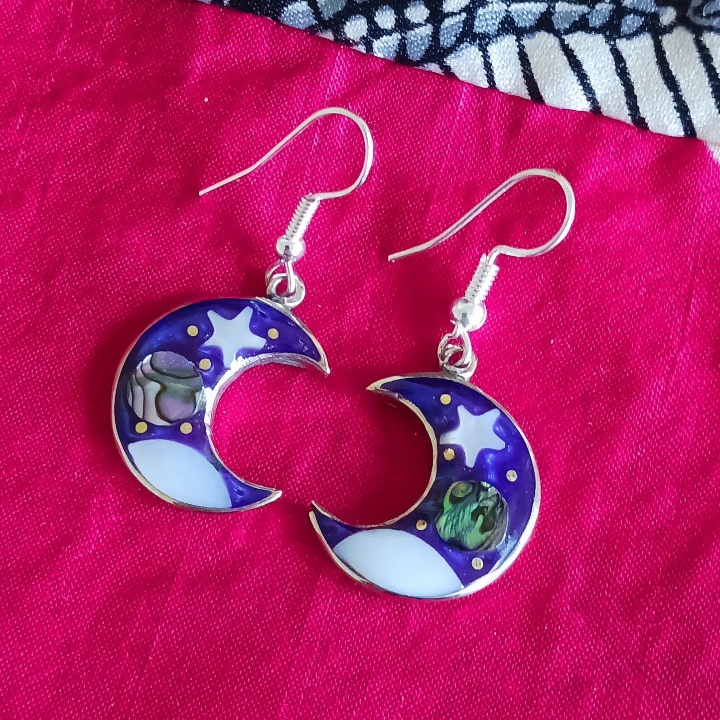 This set of beautiful celestial themed earrings are hand crafted in Taxco, Mexico. Utilising a eye-catching crescent moon design created using traditional Alpaca steel as the frame. These earrings have a celestial theme created using dyed, iridescent abalone shell.