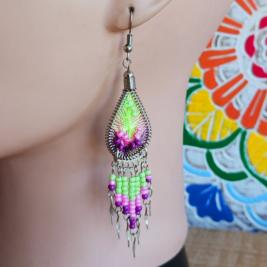 Add a splash of colour to your look with these beautiful handmade Peruvian woven teardrop earrings. Inspired by the vibrant colours and patterns of a peacock feather, each earring features intricate woven detailing complemented by coordinating beads and delicate silver-tone embellishments.