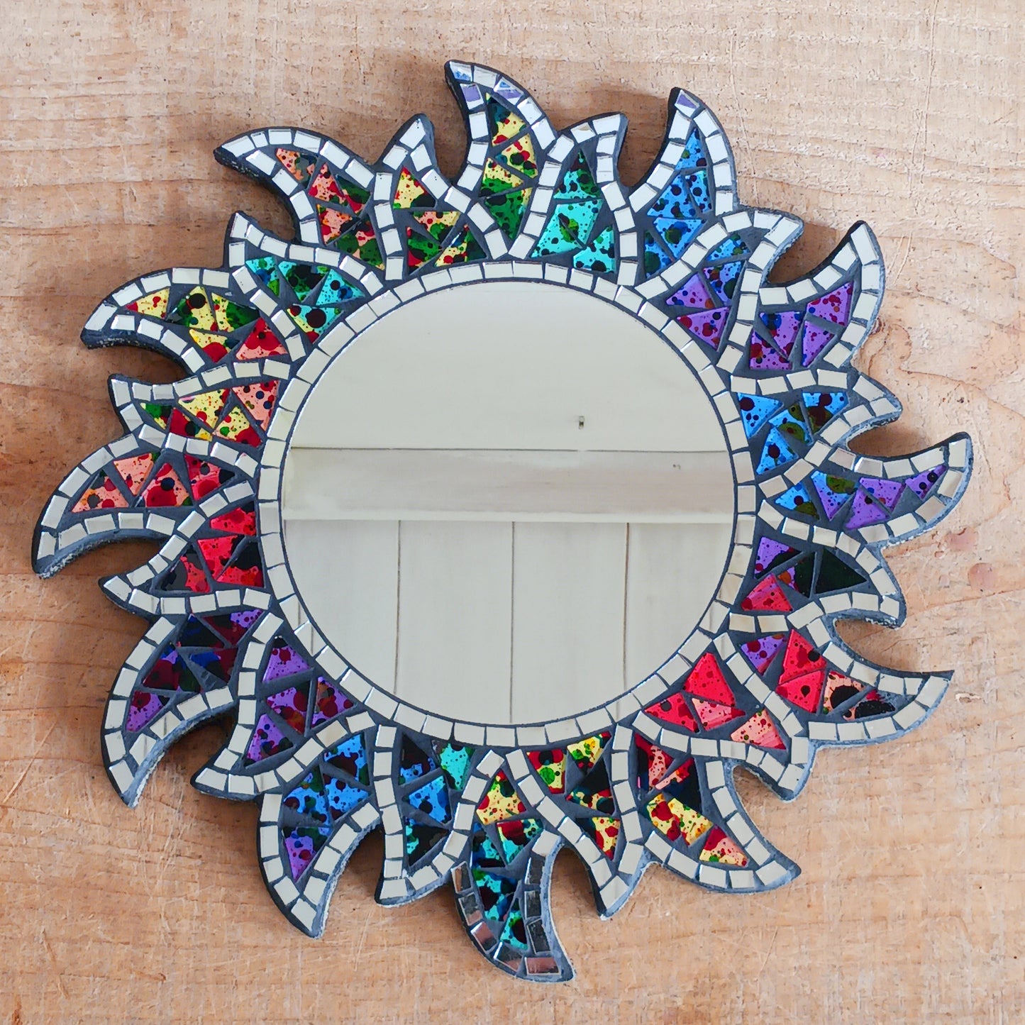 This beautiful sun shaped mirror is decoration with multicoloured glass mosaic tiles and finished on albesia wood frame.