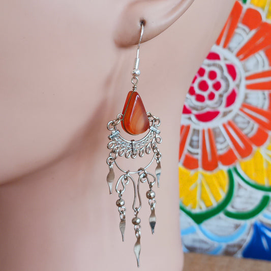 Add a touch of bohemian beauty to your look with these handmade Peruvian stone earrings. Featuring orange stones and finished with silver-plated hooks, each pair is carefully crafted in small workshops in Peru.