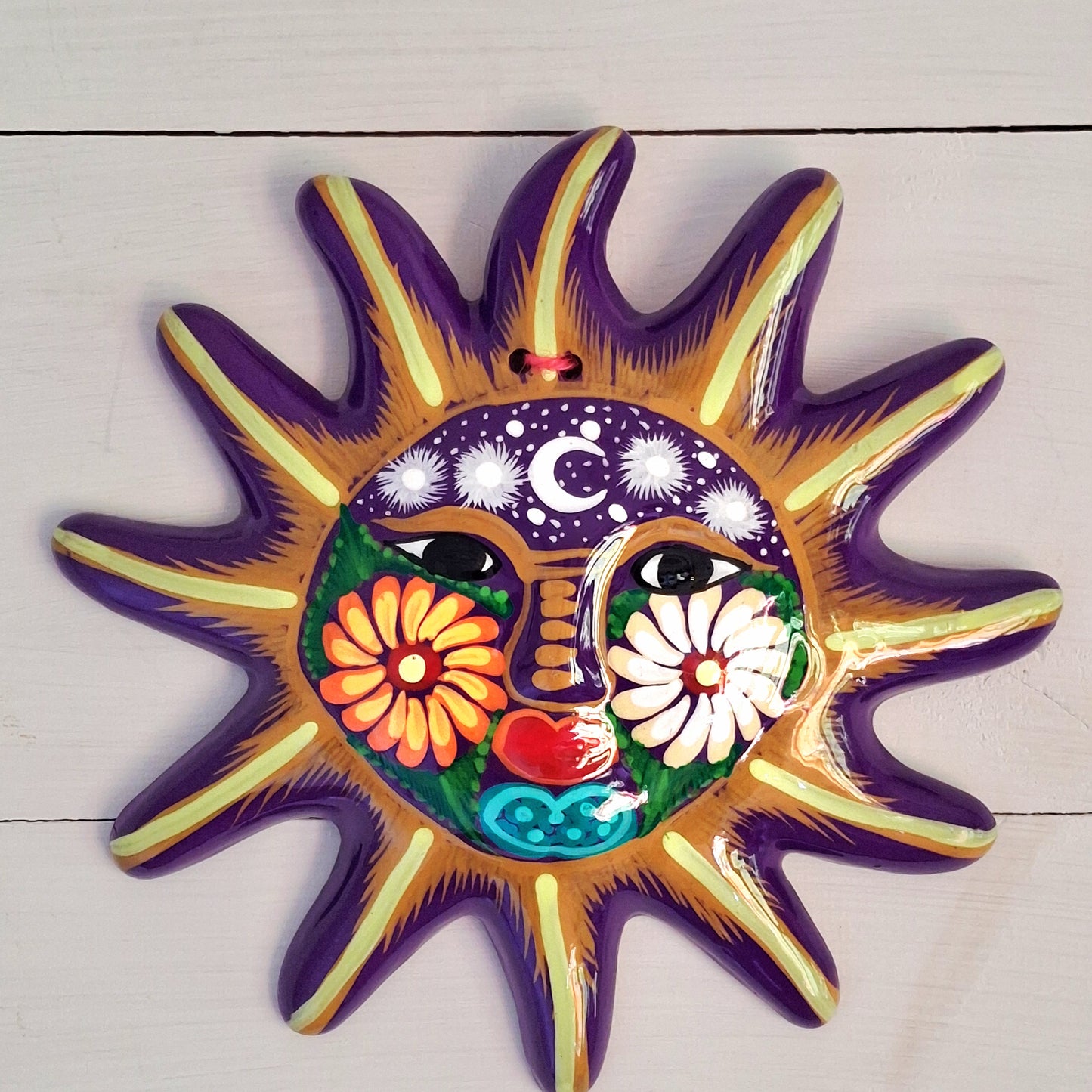 This sunny and vibrant wall plaque will get you smiling! It has been beautifully hand painted in a bright style traditional to Xalitla, a region of Guerrero, Mexico. A striking glaze adds to the bold design. It has two holes which can be used to add a hanging loop for an easy display.