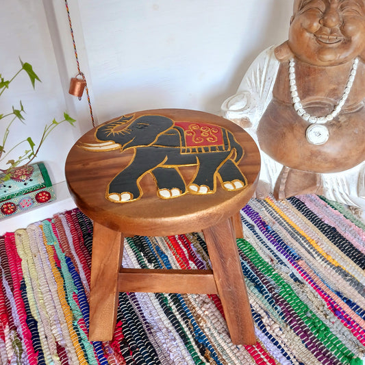 This sturdy little foot stool is from northern Thailand and features a lovely hand carved image of a festival elephant with gold paint detail. The stool is made from sustainable acacia wood. It is strong enough to sit on, use as a plant stand or purely for decoration.