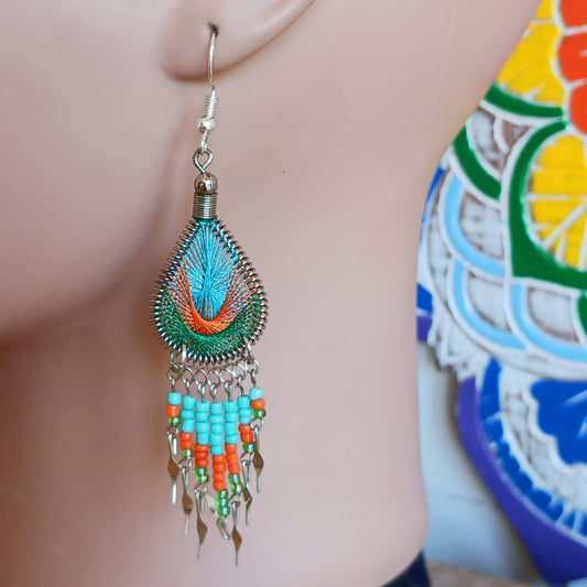These beautiful and eye-catching earrings are handmade in Peru and feature an array of gorgeous colours. A woven teardrop, similar in style to a peacock feather, is finished with co-ordinating beads and silver embellishments. Ideal for a night out or for dressing up your boho look!