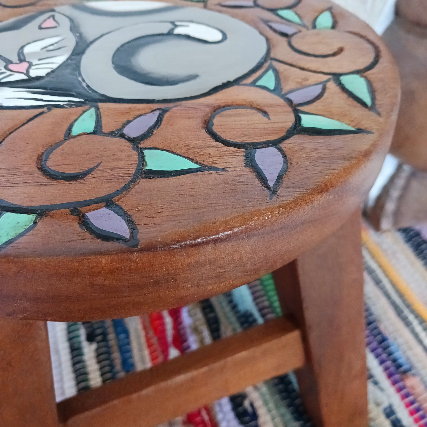 This lovely little handmade, carved and painted stool is Fairtrade from Thailand. The top of this stool has been carefully hand carved and then painted to show a peacefully curled, sleeping cat surrounded by comfy leaves. These cheeky little items are very versatile making great stools for little bums or as tiny tables to add accent to your home.