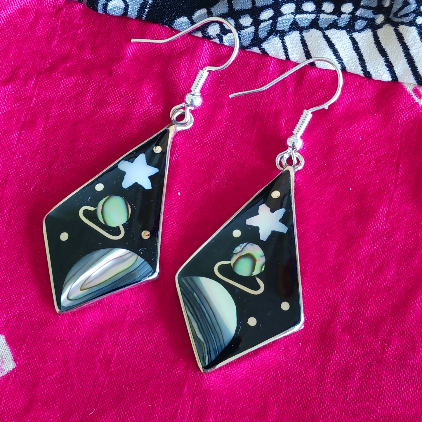 These large diamond shaped earrings feature a cosmic space scene of stars, moons and the planet Saturn crafted from mesmerising abalone shell.