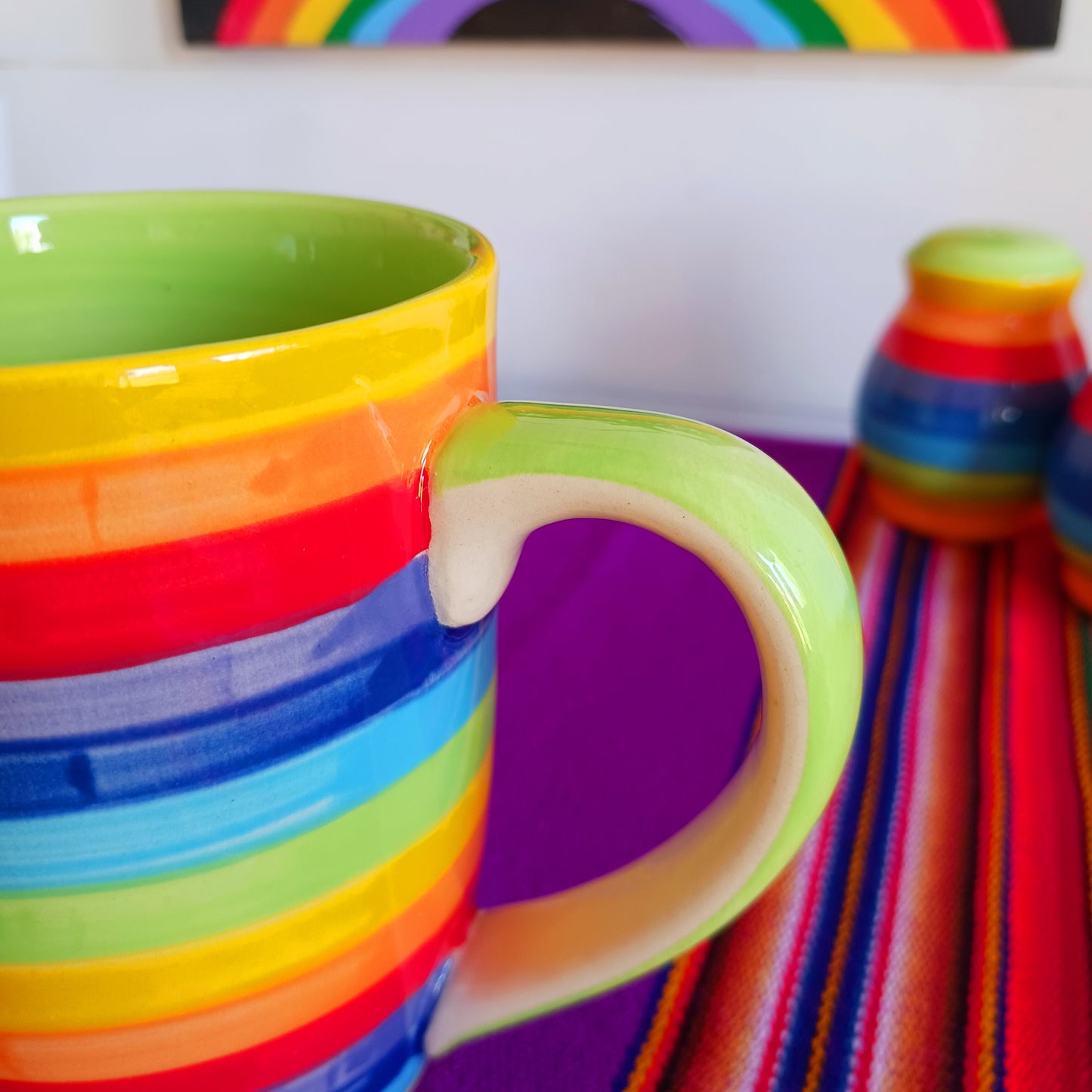The rainbow stripe on this colourful large mug is hand painted before it is fired and finishes it beautifully. These Thai ceramics are traditionally made, hand painted with a pale green interior and finished to a shine glaze highlighting the vibrant multi colors perfectly.