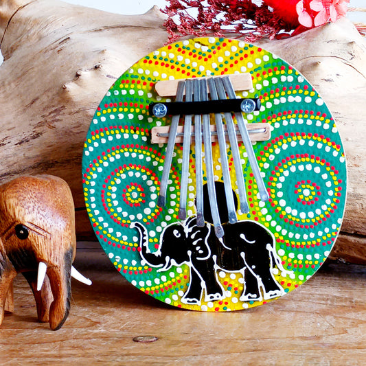 This thumb piano has been hand carved out of coconut shell and decorated with vibrant colour dot painting of an elephant. The piano board itself has been placed over a polished half coconut, which creates a resonating chamber that produces a louder, more harmonically complex sound. It has 7 keys which are adjustable and easy to tune by tightening or loosening the screws on the top.