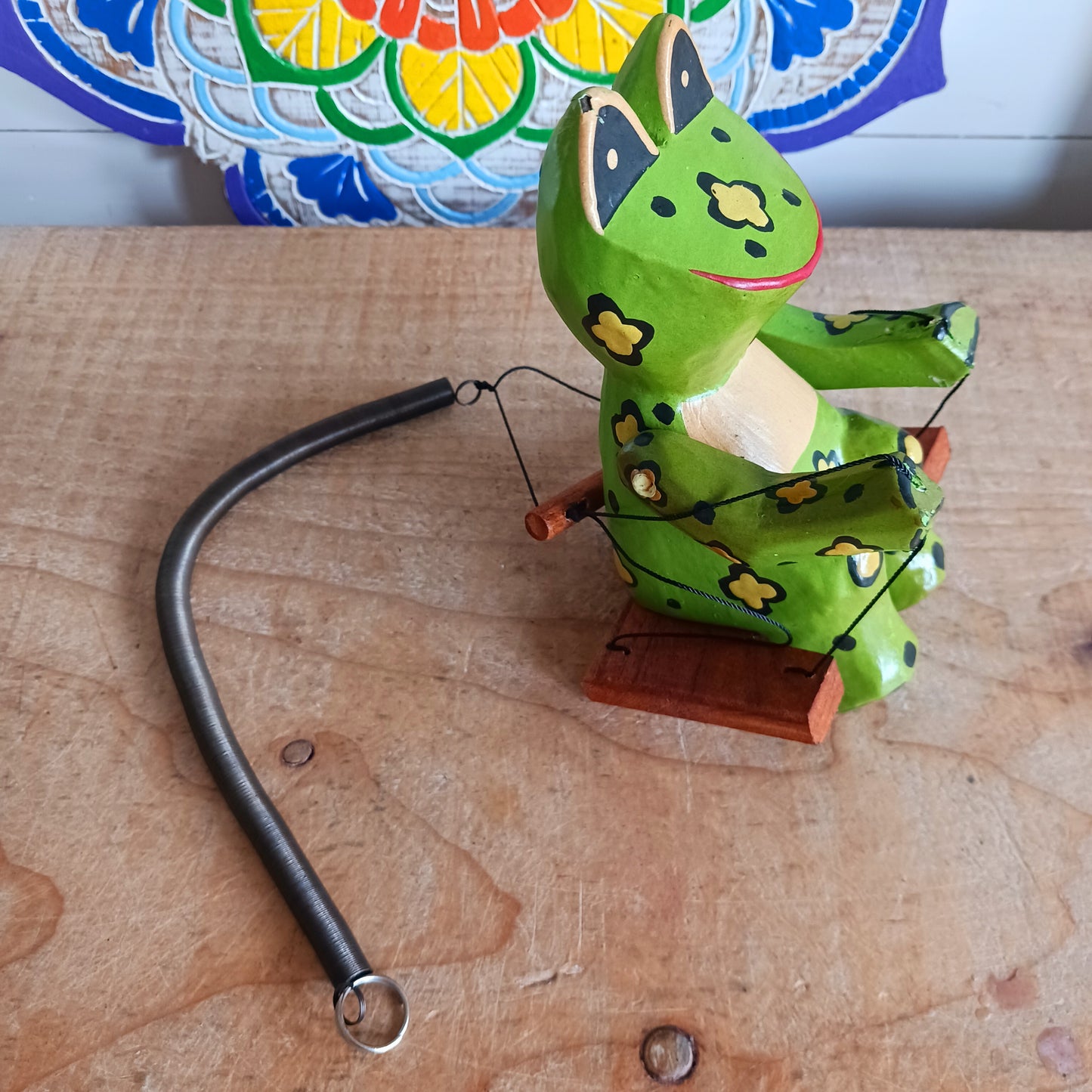 Add charm and whimsy to any space with this adorable hand-carved wooden frog! Perched on a swing and suspended by a long spring, this frog bounces gently in the air, bringing playful motion and joy to any room. Each piece is carefully hand-painted and carved from fast-growing, sustainably harvested albesia wood, making it a more eco-friendly choice for softwood décor. Whether for a nursery, porch, or creative space, this eye-catching novelty is sure to delight kids and adults alike!