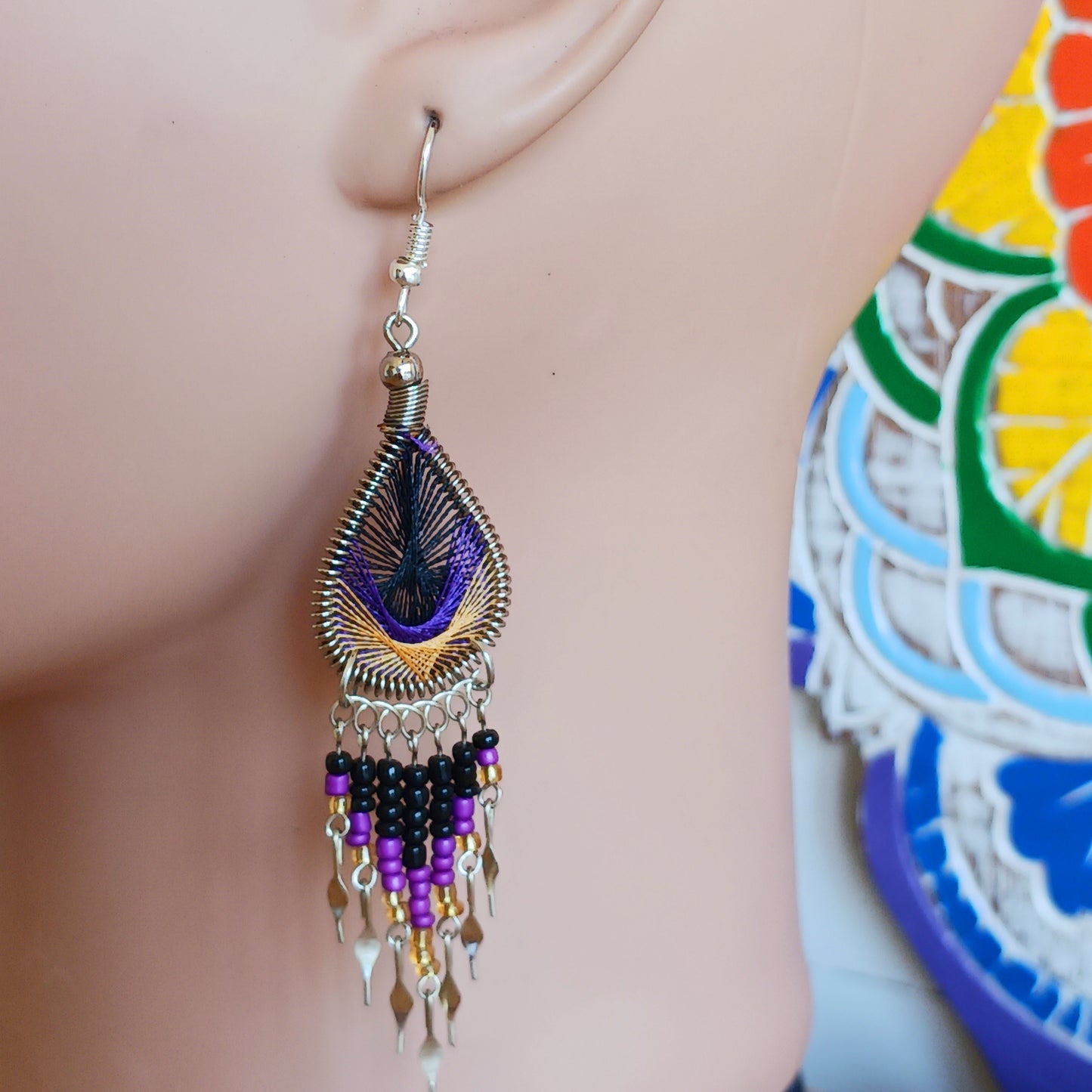 These beautiful and eye-catching earrings are handmade in Peru and feature an array of gorgeous colours. A woven teardrop, similar in style to a peacock feather, is finished with co-ordinating beads and silver embellishments. Ideal for a night out or for dressing up your boho look!