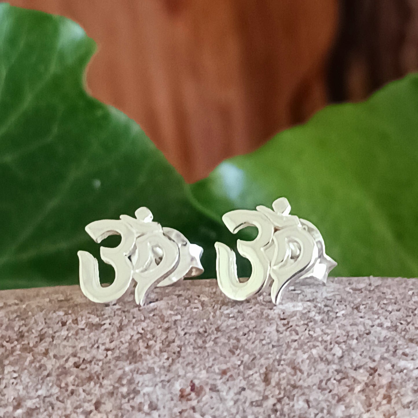 Om, a sacred mantra intoned at the beginning and end of prayers or used in meditation practices, is depicted in script in these stud earrings.