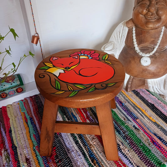 This lovely little handmade, carved and painted stool is Fairtrade from Thailand. The top of this stool has been carefully hand carved and then painted to show a peacefully curled, sleeping fox surrounded by a flower and leaves. These cheeky little items are very versatile making great stools for little bums or as tiny tables to add accent to your home.