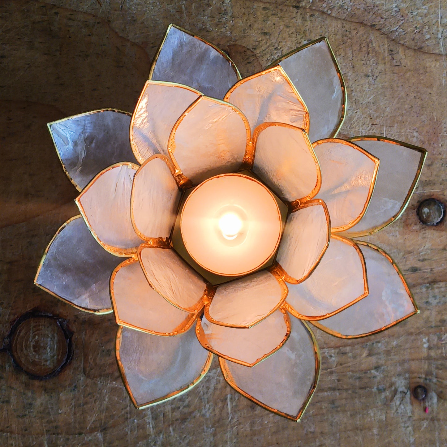 Elegant lotus candle holder made from Capiz shells. Fits 5.5cm candles. Fairtrade, handcrafted, perfect for peaceful indoor & outdoor ambiance.