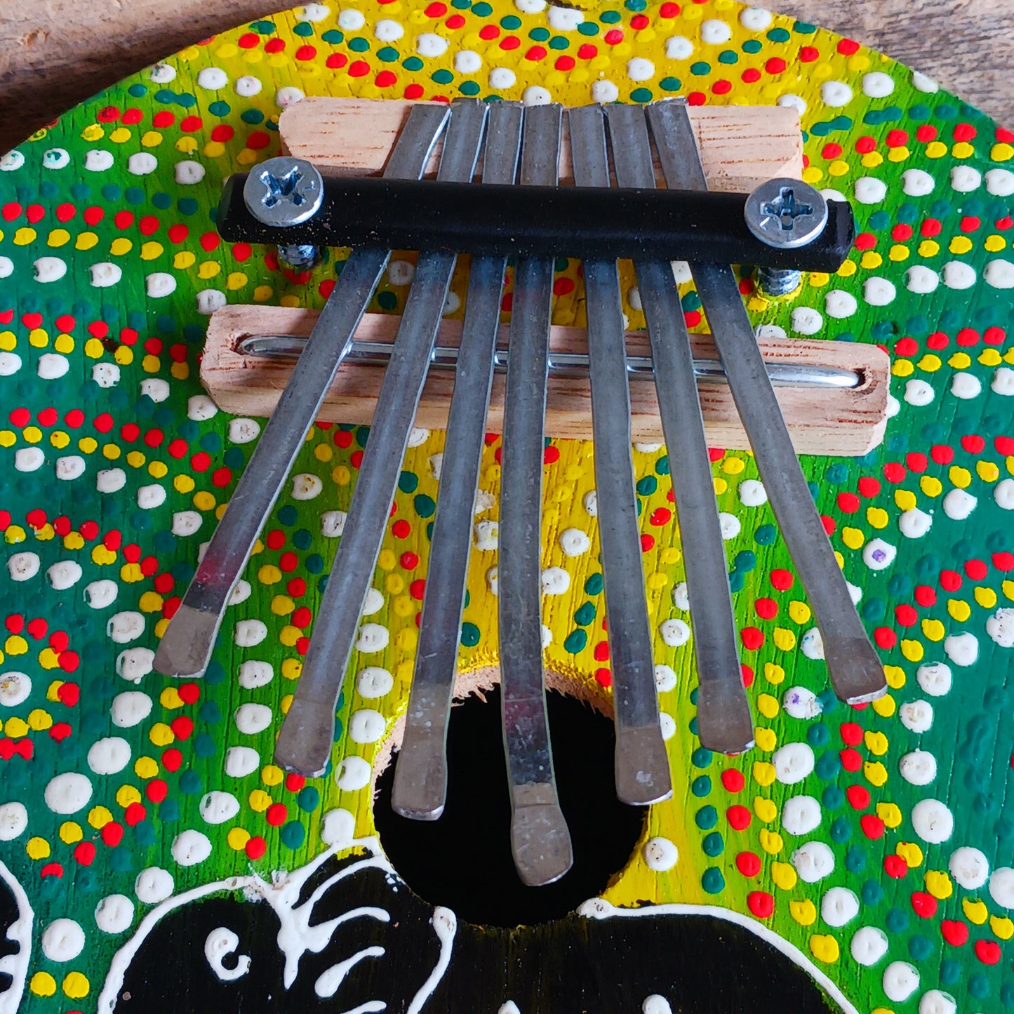 This thumb piano has been hand carved out of coconut shell and decorated with vibrant colour dot painting of an elephant. The piano board itself has been placed over a polished half coconut, which creates a resonating chamber that produces a louder, more harmonically complex sound. It has 7 keys which are adjustable and easy to tune by tightening or loosening the screws on the top.