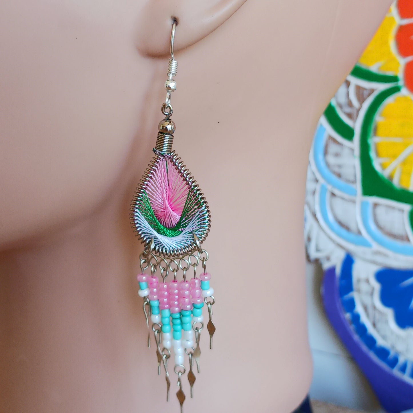 These beautiful and eye-catching earrings are handmade in Peru and feature an array of gorgeous colours. A woven teardrop, similar in style to a peacock feather, is finished with co-ordinating beads and silver embellishments. Ideal for a night out or for dressing up your boho look!