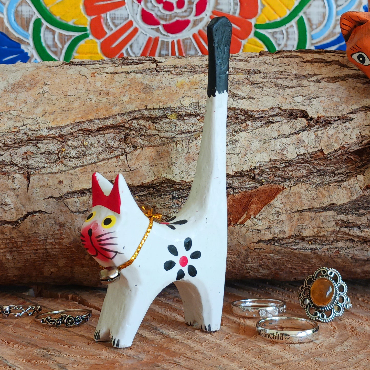 Cat-shaped jewelry holder with rings on a wooden surface